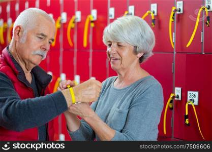 elderly couple attaching locker bracelet around wrist