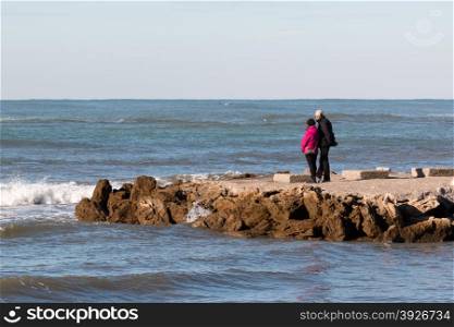 elderly couple enjoy the view on seacoast in winter, sea contemplation