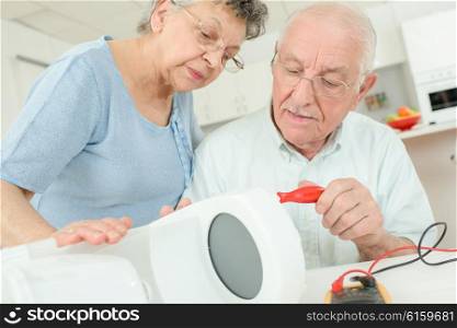 elderly couple fixing coffee maker
