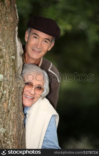 Elderly couple hiding behind a tree