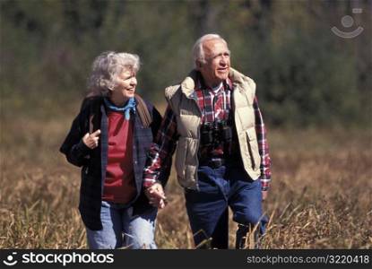Elderly Couple Hiking Through Brush