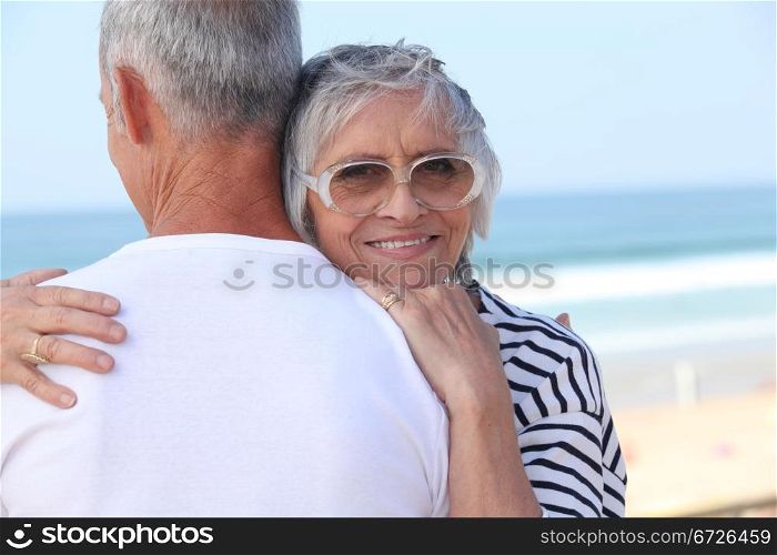 Elderly couple hugging by a beach