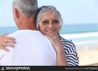 Elderly couple hugging by a beach
