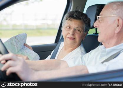 elderly couple in the car with a map
