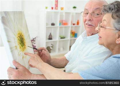 Elderly couple looking at painting of a sunflower