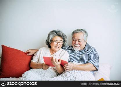 Elderly Couple Lying on the bed and reading a book