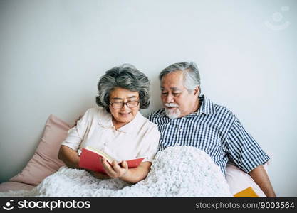 Elderly Couple Lying on the bed and reading a book