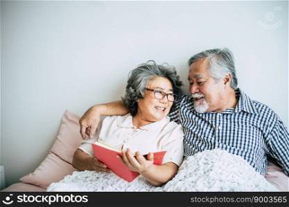 Elderly Couple Lying on the bed and reading a book