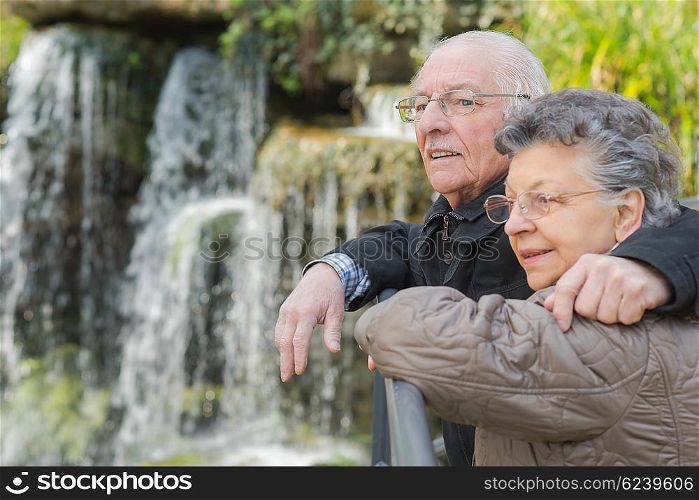 elderly couple next to a waterfalls