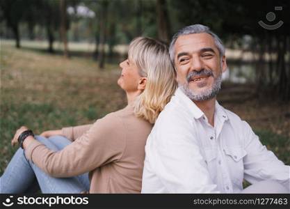 Elderly couple of sitting back to back relax together in the public park. Happy concept of lifestyle in the family holiday