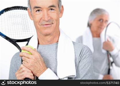 Elderly couple playing tennis together