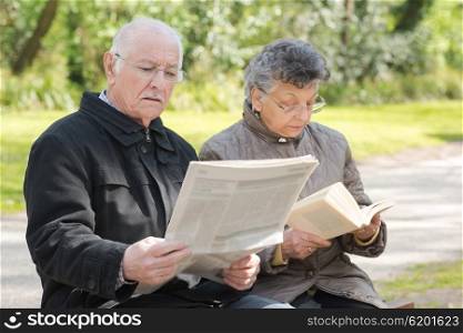elderly couple reading in the park