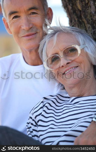 Elderly couple stood by tree in park