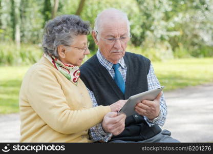 elderly couple with a tablet in the park