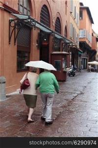 elderly couple with an umbrella on a street in Bologna
