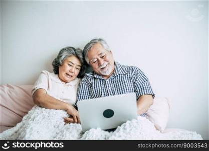Elderly couples talking and using laptop in bedroom