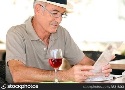 elderly gentleman seated in cafe drinking glass of red wine