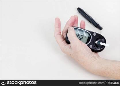 Elderly hands holding blood sugar level machine, checking reading
