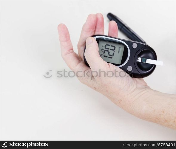 Elderly hands holding blood sugar level machine, checking reading