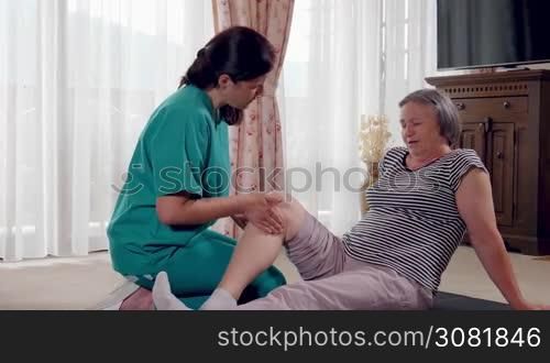Elderly lady being rehabilitated by a physiotherapist at home. Senior during rehabilitation with physiotherapist after leg injury. Slow motion hand held movement