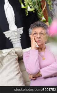 Elderly lady holding tissue, looking sad