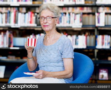 Elderly lady in the libary with cup of tea. Few minutes for tea