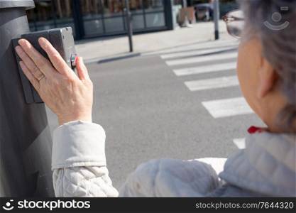 Elderly lady pushing button at pedestrian crossing