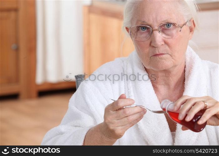 Elderly lady taking medication in kitchen