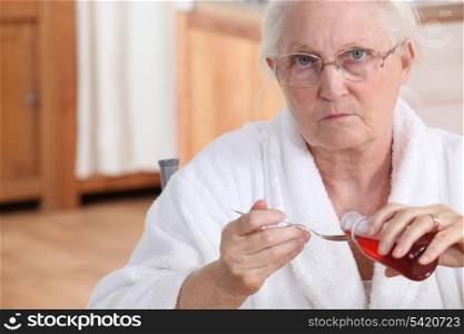 Elderly lady taking medication in kitchen