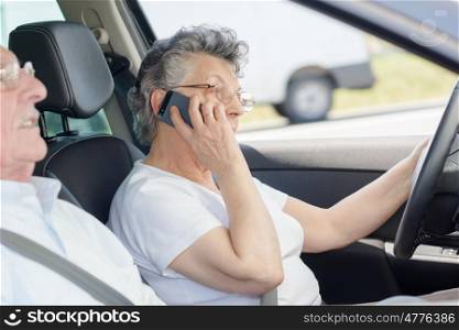 Elderly lady using mobile phone while driving
