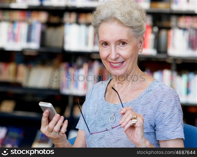 Elderly lady with mobile phone in library. Calling my friends