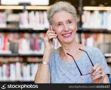 Elderly lady with mobile phone in library. Calling my friends