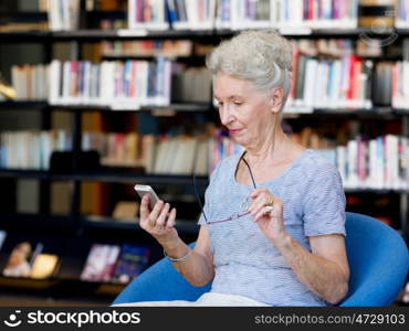 Elderly lady with mobile phone in library. Calling my friends