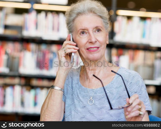 Elderly lady with mobile phone in library. Calling my friends