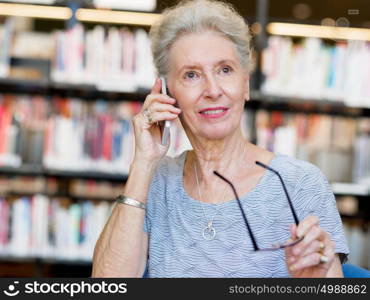 Elderly lady with mobile phone in library. Calling my friends