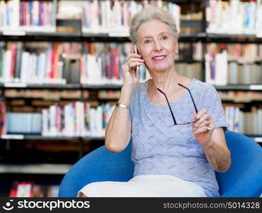 Elderly lady with mobile phone in library. Calling my friends