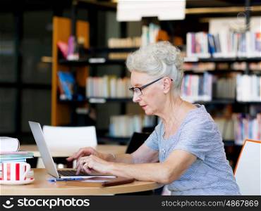 Elderly lady working with laptop. Learning new technologies