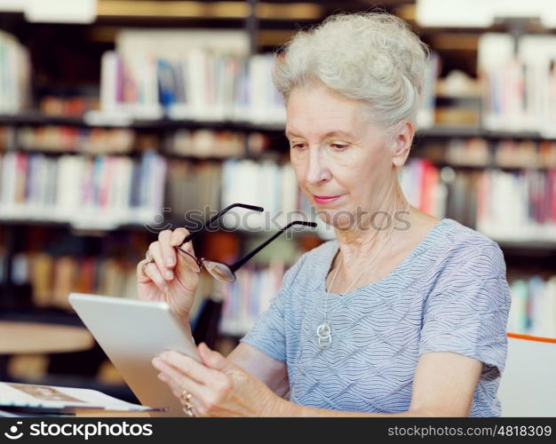 Elderly lady working with tablet. Learning new technologies