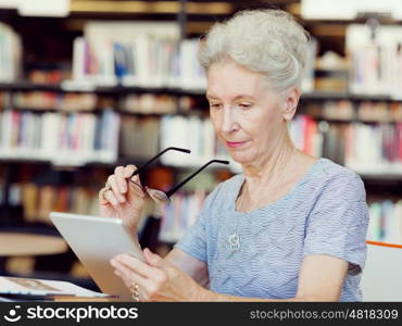 Elderly lady working with tablet. Learning new technologies