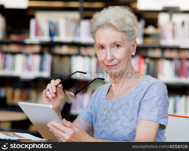 Elderly lady working with tablet. Learning new technologies