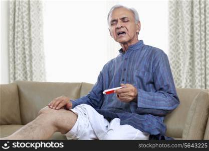 Elderly man applying ointment on knee