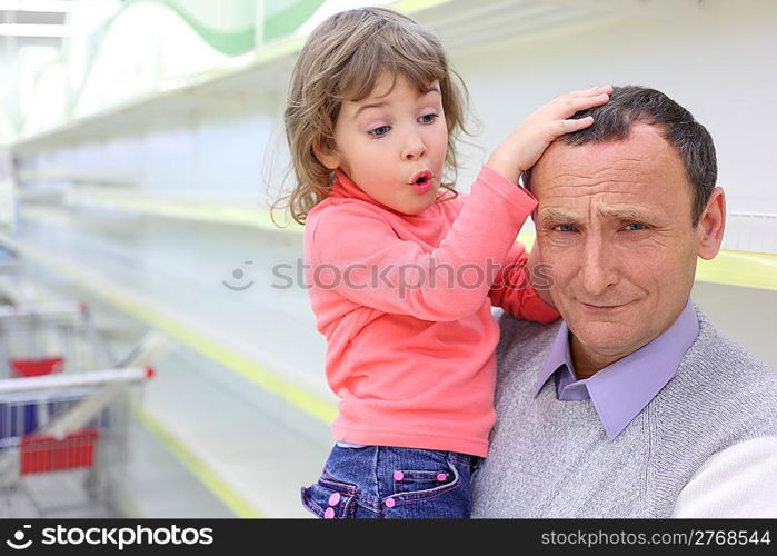 elderly man at empty shelves in shop with child on hands, grand daughter feels sorry for grandfather