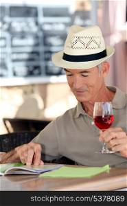Elderly man drinking a glass of rose in a cafe
