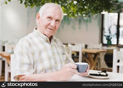 elderly man drinking tea looking camera