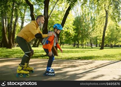 Elderly man enjoying sports in sunny summer park with his little son. Happy overjoyed father following boy riding roller skates. Elderly man enjoying sports in sunny summer park with his little son