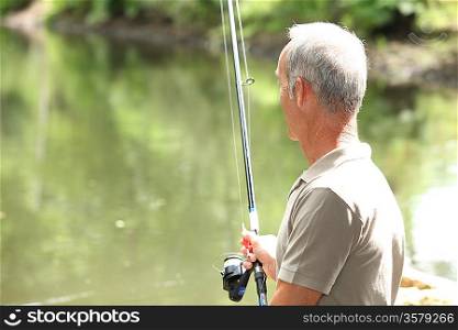elderly man fishing by river