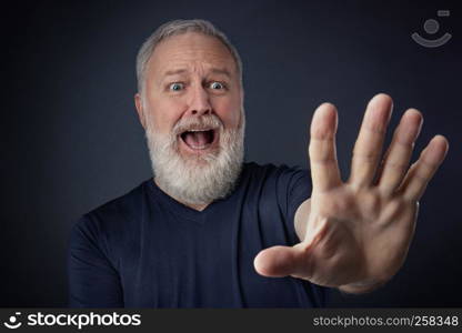 Elderly man in shirt and scared with his stretched hand forward for stopping something