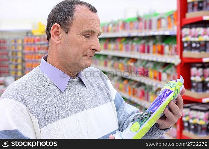 elderly man in shop with package in hands