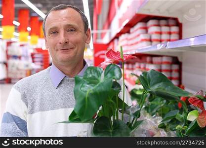 elderly man in shop with plant in hand