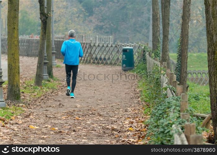 Elderly man jogging in park in autumn. Health and fitness